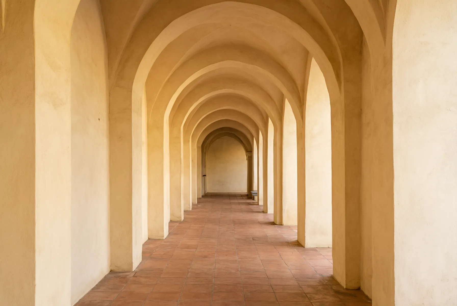 A sunlit terracotta colonnade of rounded arches